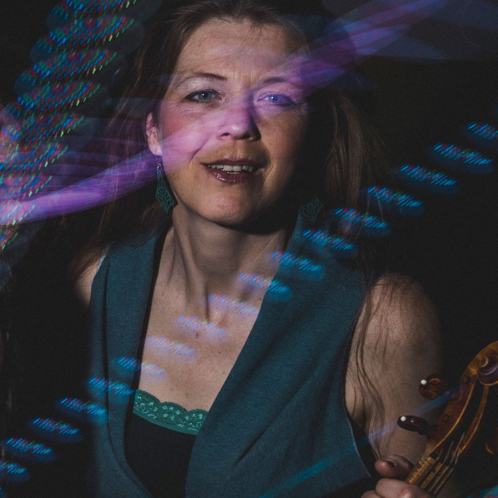 Portrait photo of violinist, smiling and holding a violin