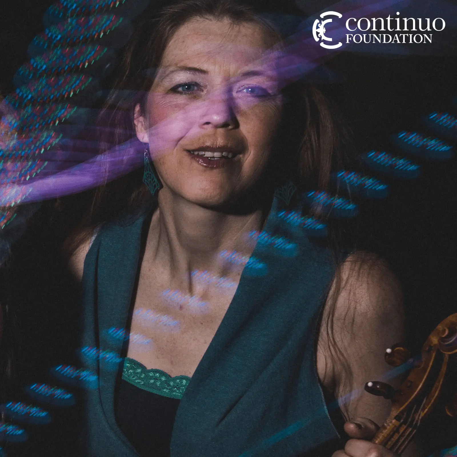 Portrait photo of violinist, smiling and holding a violin